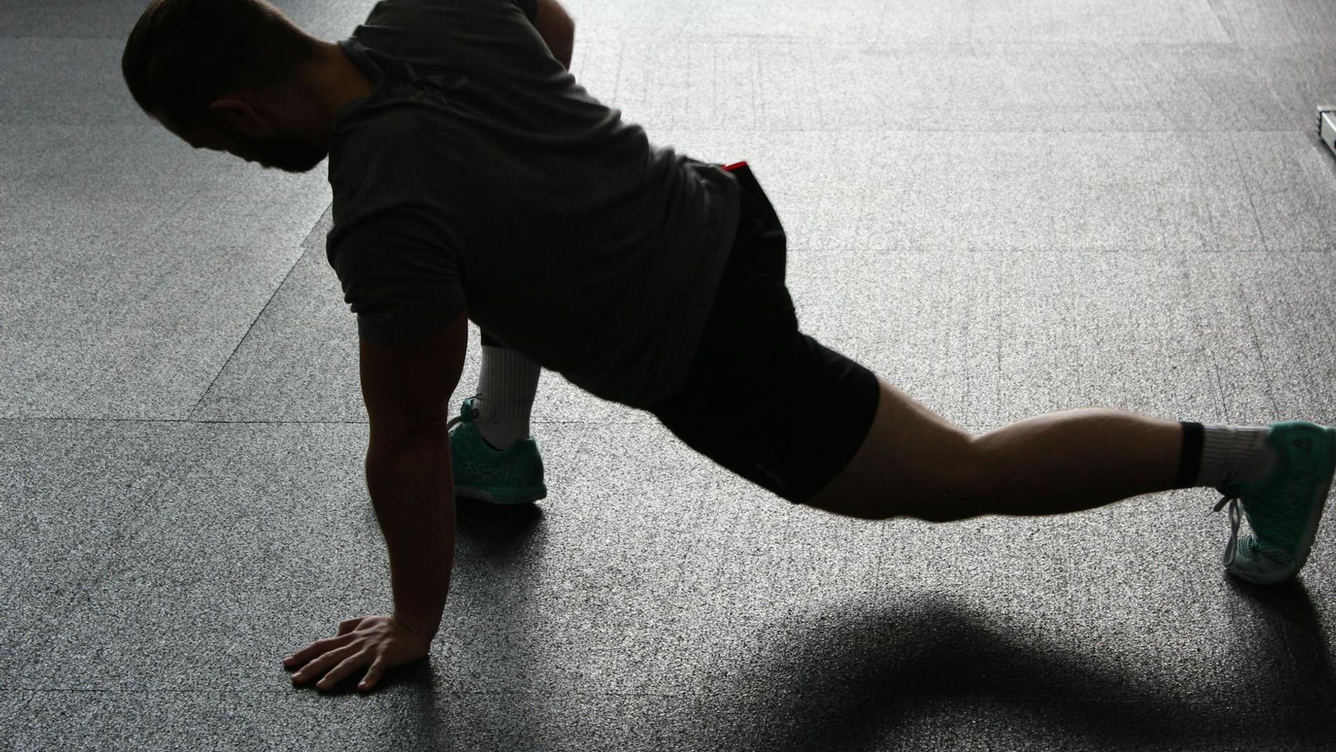 Silhouette of a man performing a dynamic strength exercise in a dark setting.
